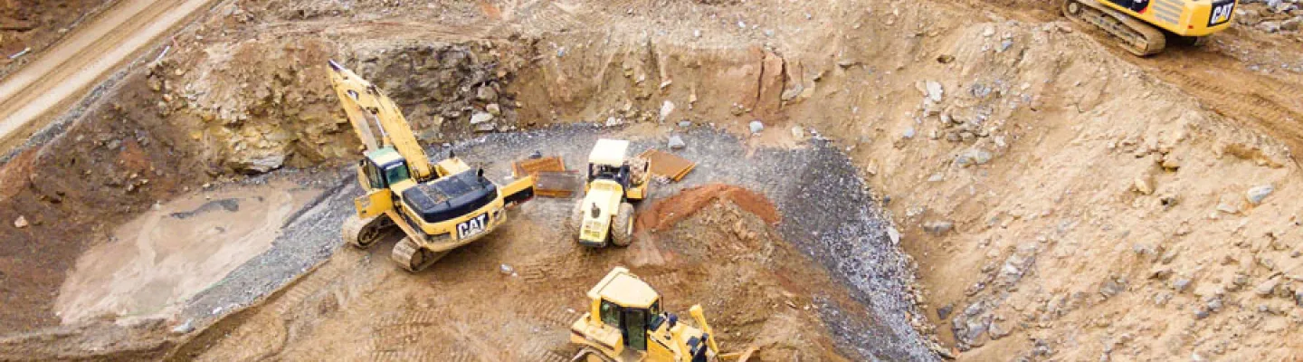 Excavators assisting construction crews on-site, with safety barriers in place to control access and protect workers.