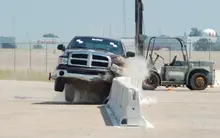Workers installing safety barriers on a road construction site to prevent vehicle collisions.