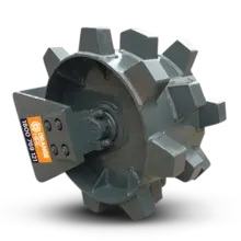 Compaction wheel attachment on an excavator, used to compress soil on a construction site with safety barriers nearby.