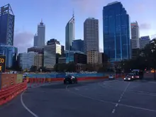 City road lined with orange safety barriers, demonstrating traffic control and pedestrian protection at a construction zone.