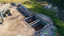 Workers on-site installing Brace-400 system in a large excavation hole, ensuring structural support and trench safety.