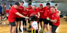Group of smiling personnel exercising together in a gym, promoting team wellness and positive workplace culture.