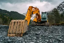 Excavator operating at a construction site, illustrating heavy machinery use in barrier setup and site preparation.