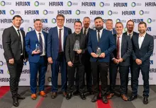 Group of employees smiling and holding an award plaque, celebrating recognition and company achievements.