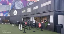 Outdoor pop-up cinema and restaurant setup with tables, a large screen, and guests enjoying a movie and meal under string lights.