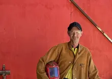 Man using welding tools at a worksite, wearing protective gear and performing metalwork as part of a construction project.