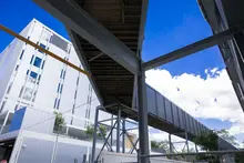 Covered hospital walkway made from long shipping containers, providing sheltered access between buildings for staff and patients.