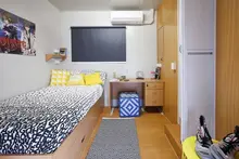 Compact modular bedroom with single bed, desk, storage, and air conditioning.