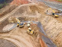 Excavators assisting construction crews on-site, with safety barriers in place to control access and protect workers.
